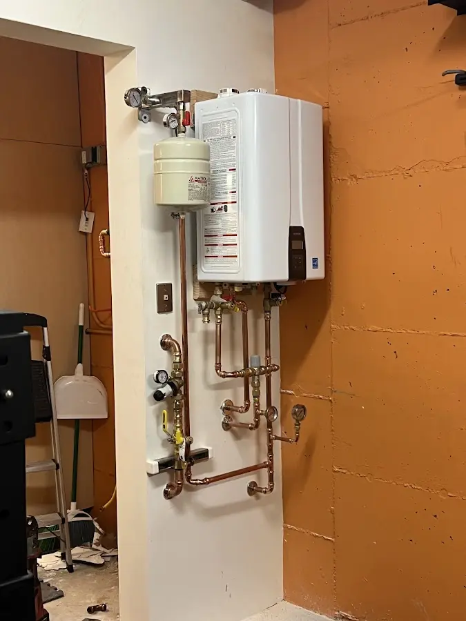Plumbing technician inspecting water heater connections in Forward